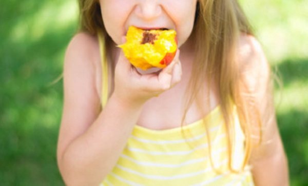 Девочка ест персики