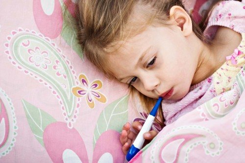 little girl lies with a thermometer in her mouth