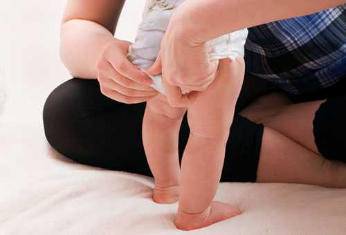 Mom adjusts baby&#39;s diaper