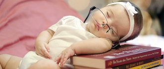 Трехмесячная девочка спит на стопке книг
